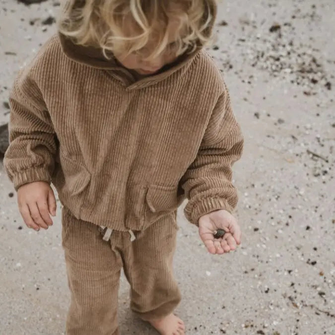 girl playing around wearing her Tan corduroy tracksuit which is has a corduroy hoodie and corduroy pants. Made from organic cotton, GOTS certified and sustainably made. front view 1