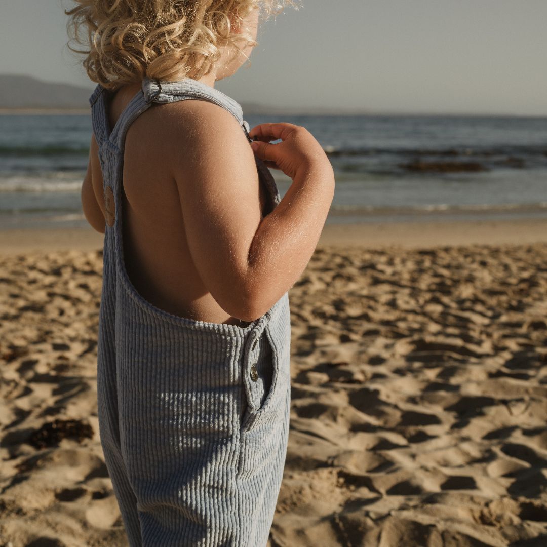 boy on the beach wearing his Kids and toddlers blue corduroy overalls or dungarees