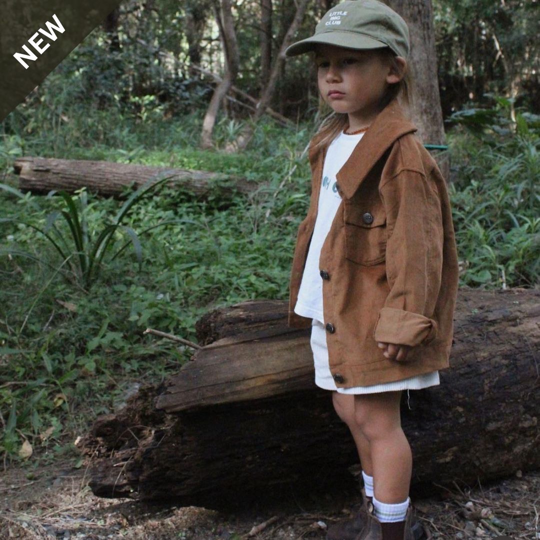 Kids and toddlers chocolate corduroy long sleeve dress shirt standing in front of a log in nature