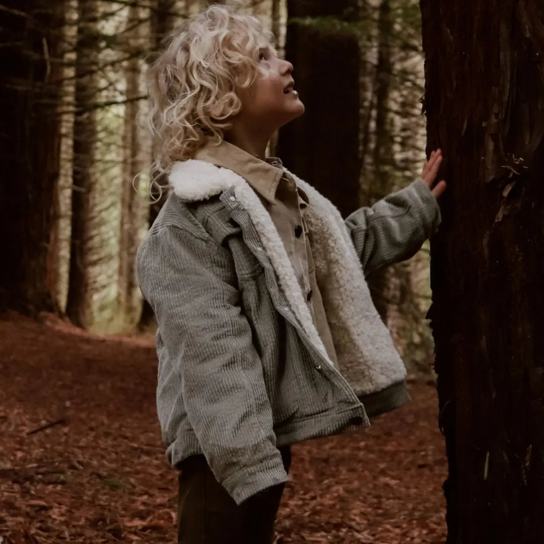 Kids and toddlers organic corduroy sherpa fleece jacket in sage with a hand on a tree looking up at it