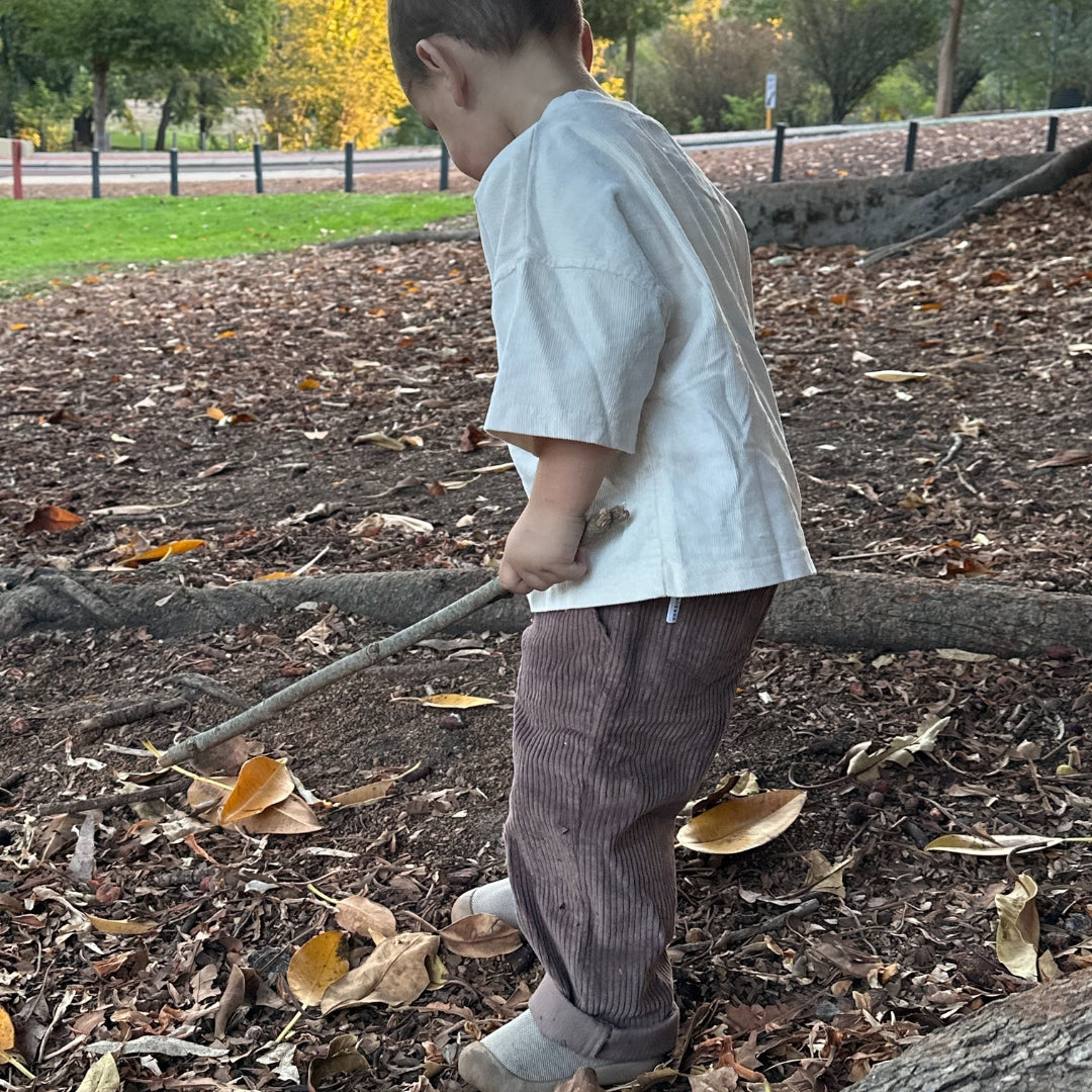 organic cotton corduroy pants in colour brown for infants, toddlers and kids sitting side view in the bush