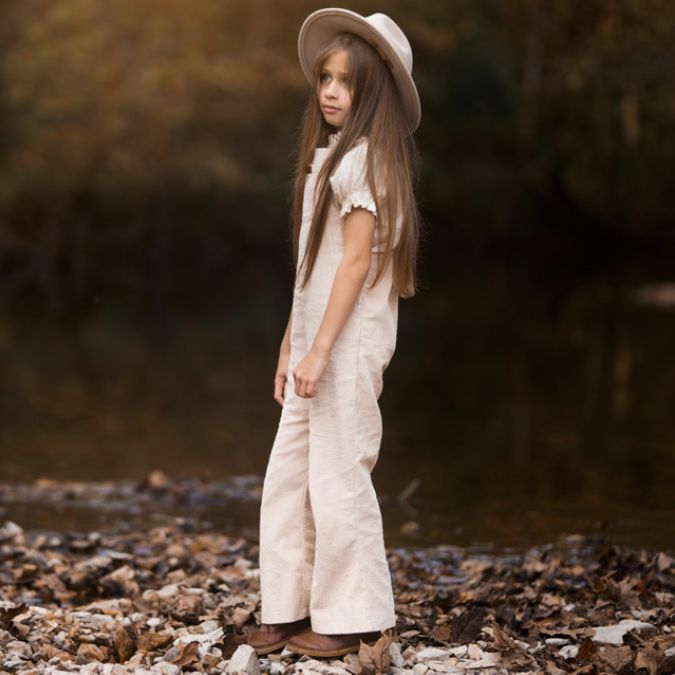girl standing on some rocks wearing her begie Kids and toddlers corudoy flare overalls or dungarees