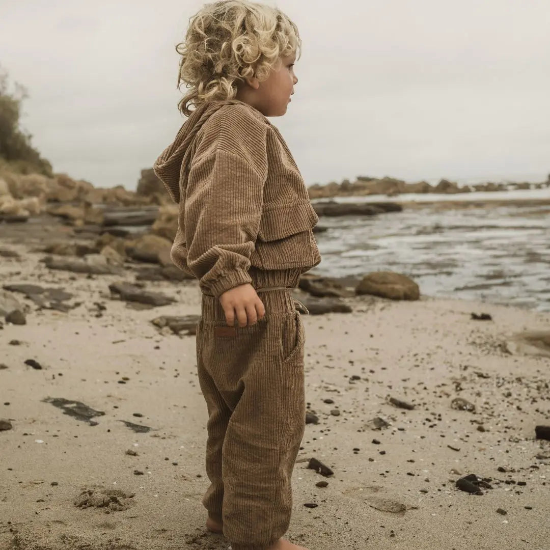 girl playing around wearing her Tan corduroy tracksuit which is has a corduroy hoodie and corduroy pants. Made from organic cotton, GOTS certified and sustainably made. side view 