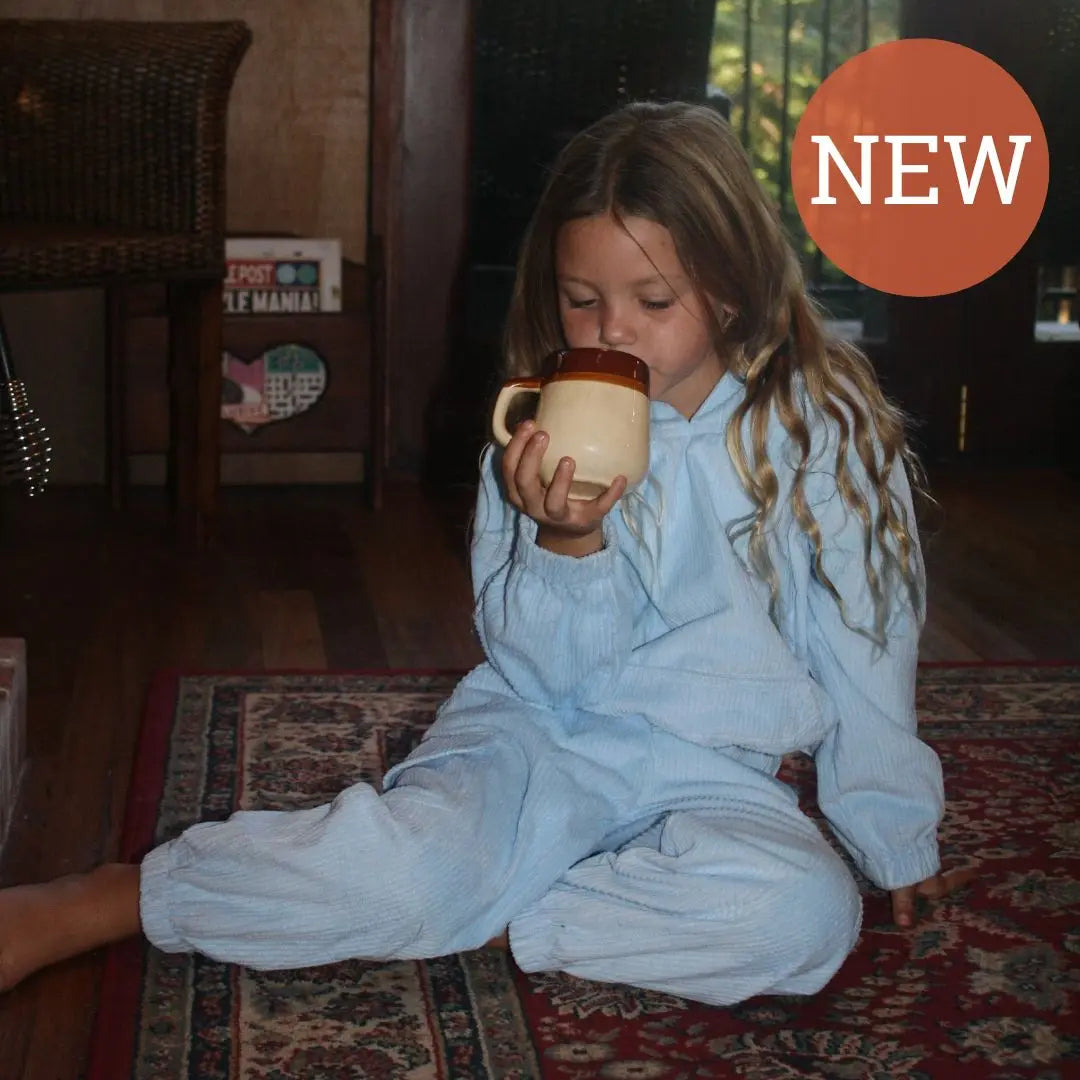 girl playing around wearing her blue corduroy tracksuit which is has a corduroy hoodie and corduroy pants. Made from organic cotton, GOTS certified and sustainably made. Front view