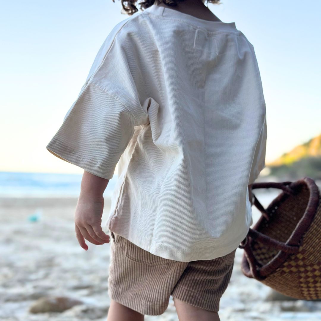 Kids and toddlers beige corduroy loose t-shirt and corduroy short standing on a beach holding a basket