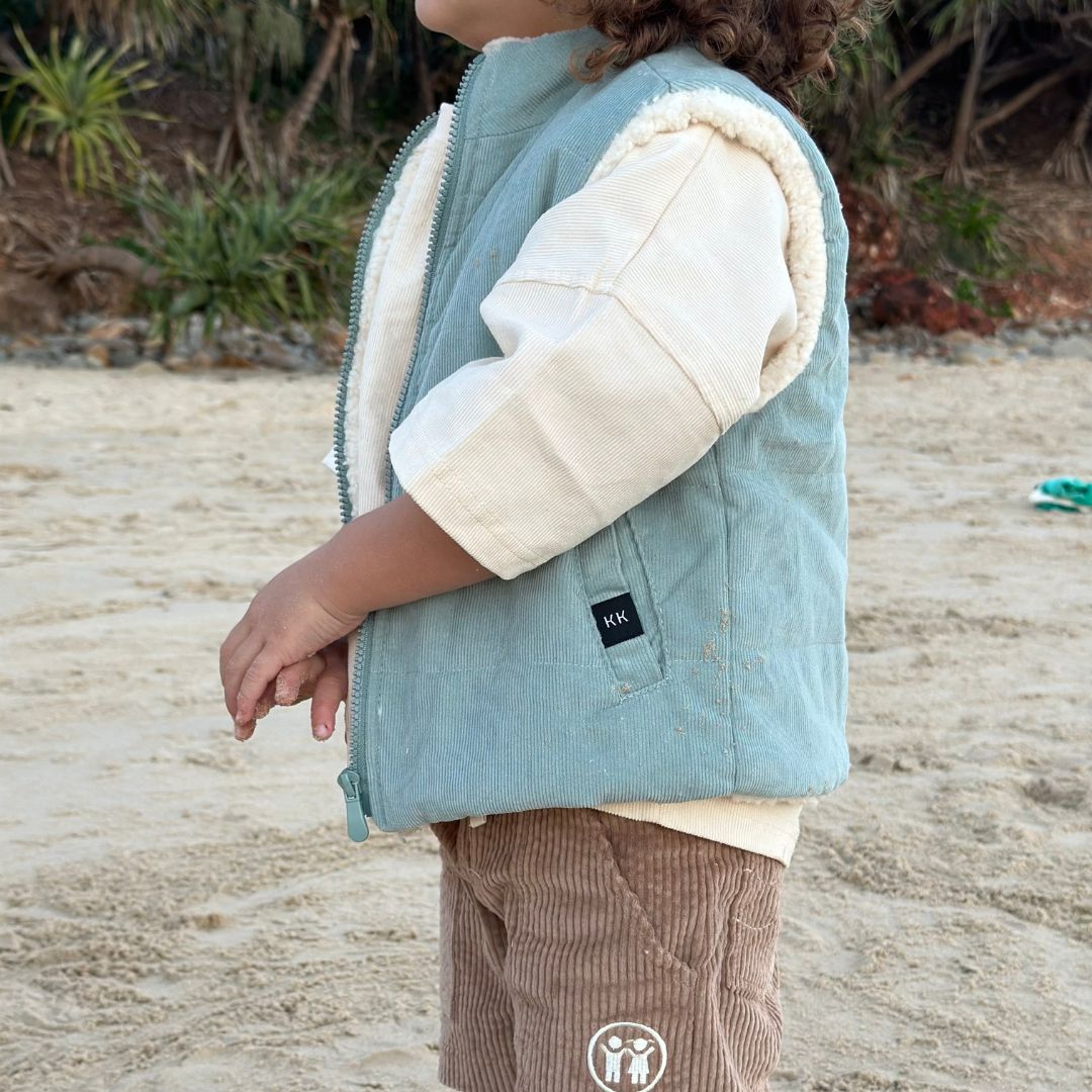 boy wearing his Kids and toddlers ocean blue colour corduroy puffer vest lined with sherpa fleece and tan corduroy shorts showing off the detail