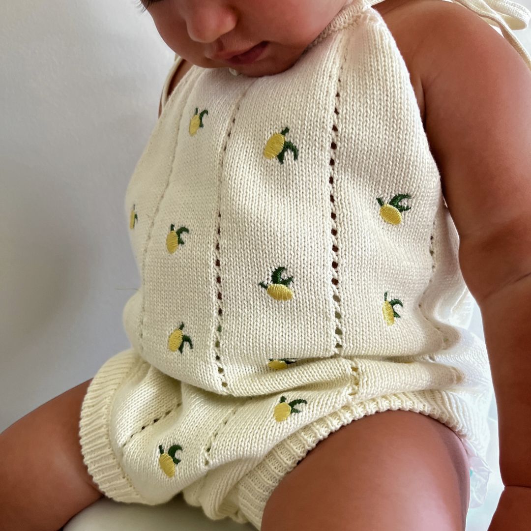 organic cotton romper for babies ages 0 - 24 months. Croquet style romper in beige with lemons embroided into it front view