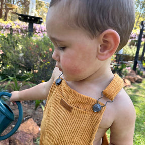 organic cotton corduroy overalls in orange for kids and toddlers. close up of front