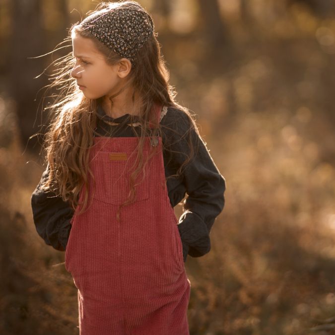 girl wearing her pink Kids and toddlers corduroy flare overalls or dungarees looking away from camera