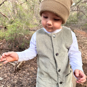 baby wearing his sage corduroy romper in nature