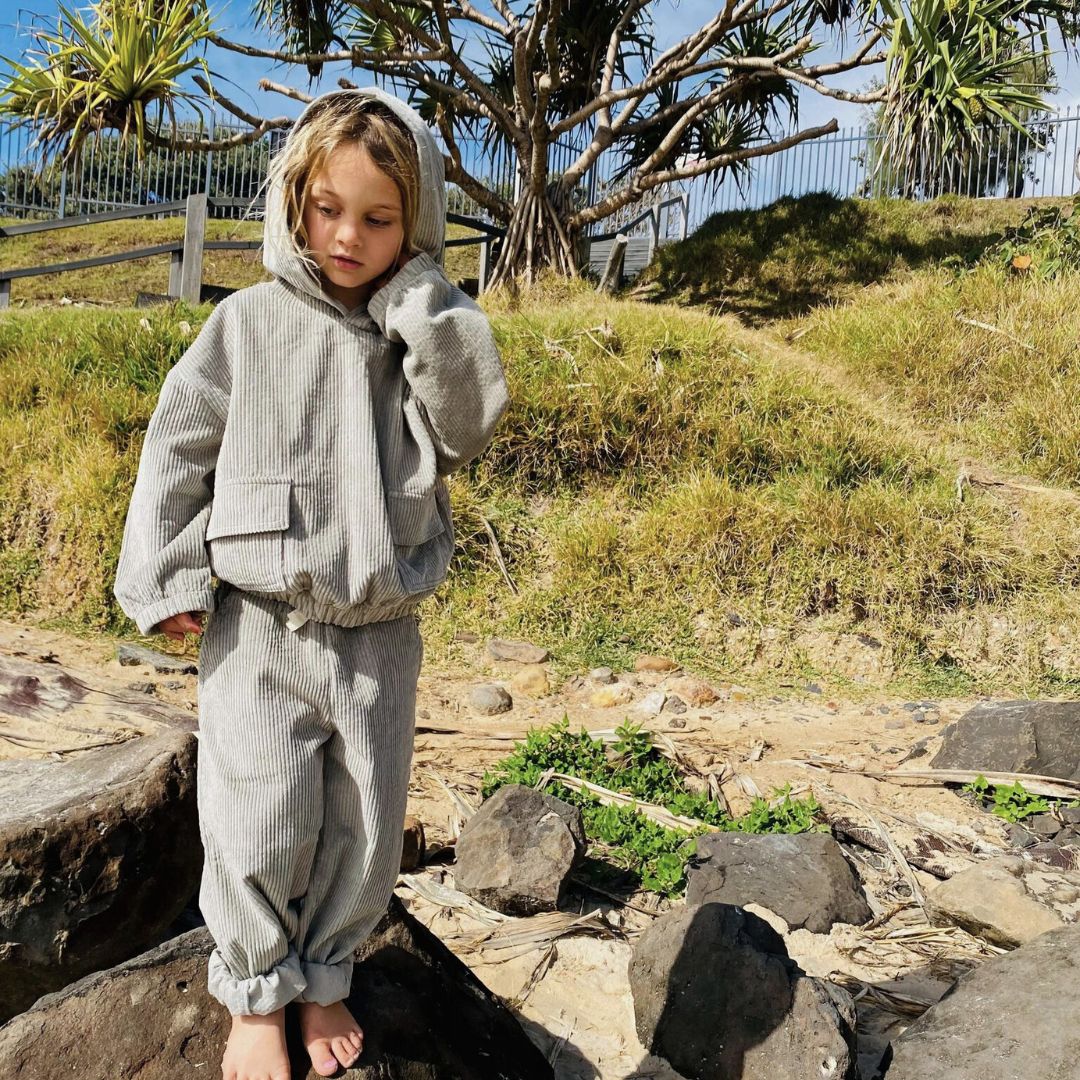 boy wearing his Kids and toddlers sage corduroy tracksuit with corduroy pants and hoodie standing on a rock at the beach