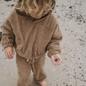 boy holding a rock wearing his Kids and toddlers tan corduroy tracksuit with his tan corduroy hoodie and tan corduroy pants